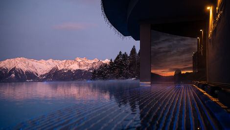 Hotel infinity pool reflecting sunset over the Dolomites, accessible to Bergvillen guests