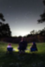 mum and two young girls sitting on camp chairs  at night looking at the stars at Jacaranda Hill campsite, peel region, Western Australia. Astroportrait