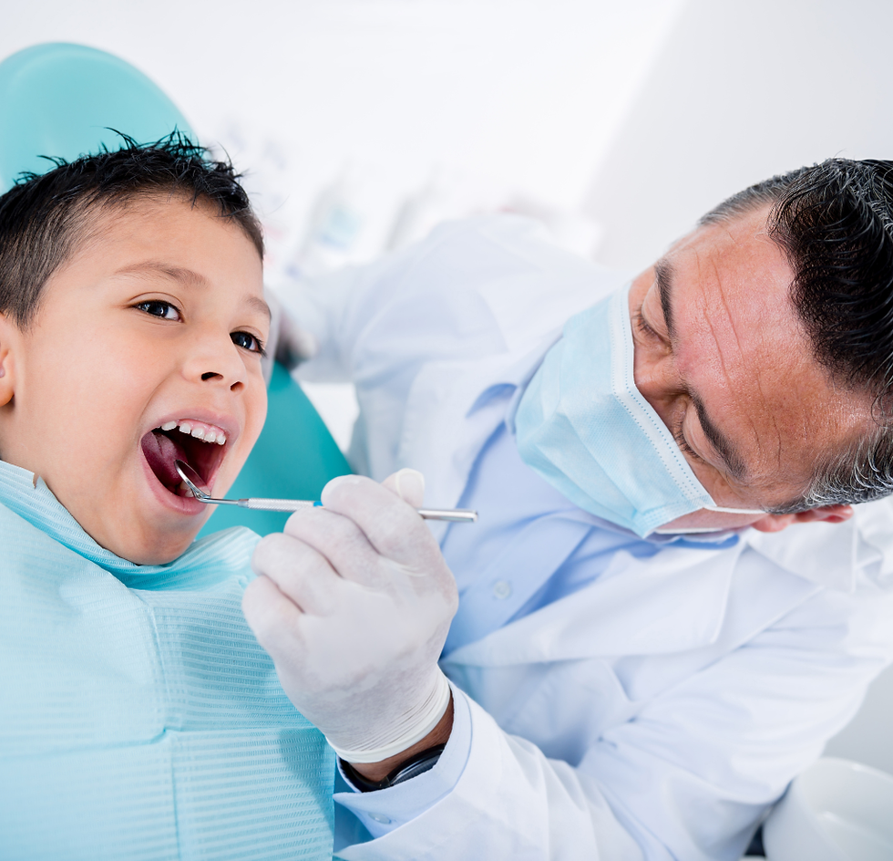 Dentist examining a young boy's teeth in a dental chair.