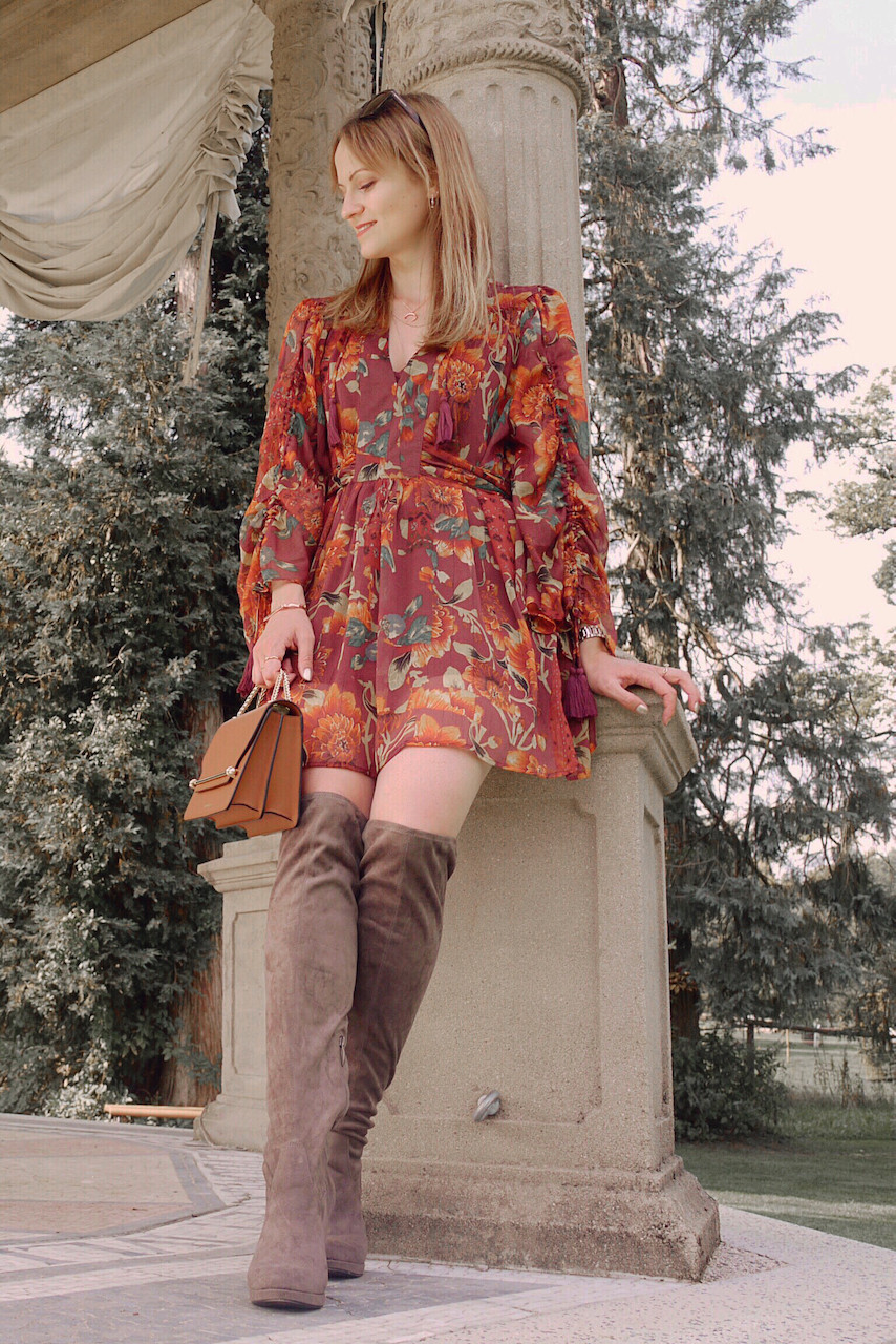 Autumn Outfit. Girl dressed in dark floral dress, over the knee boots carrying a tan bag