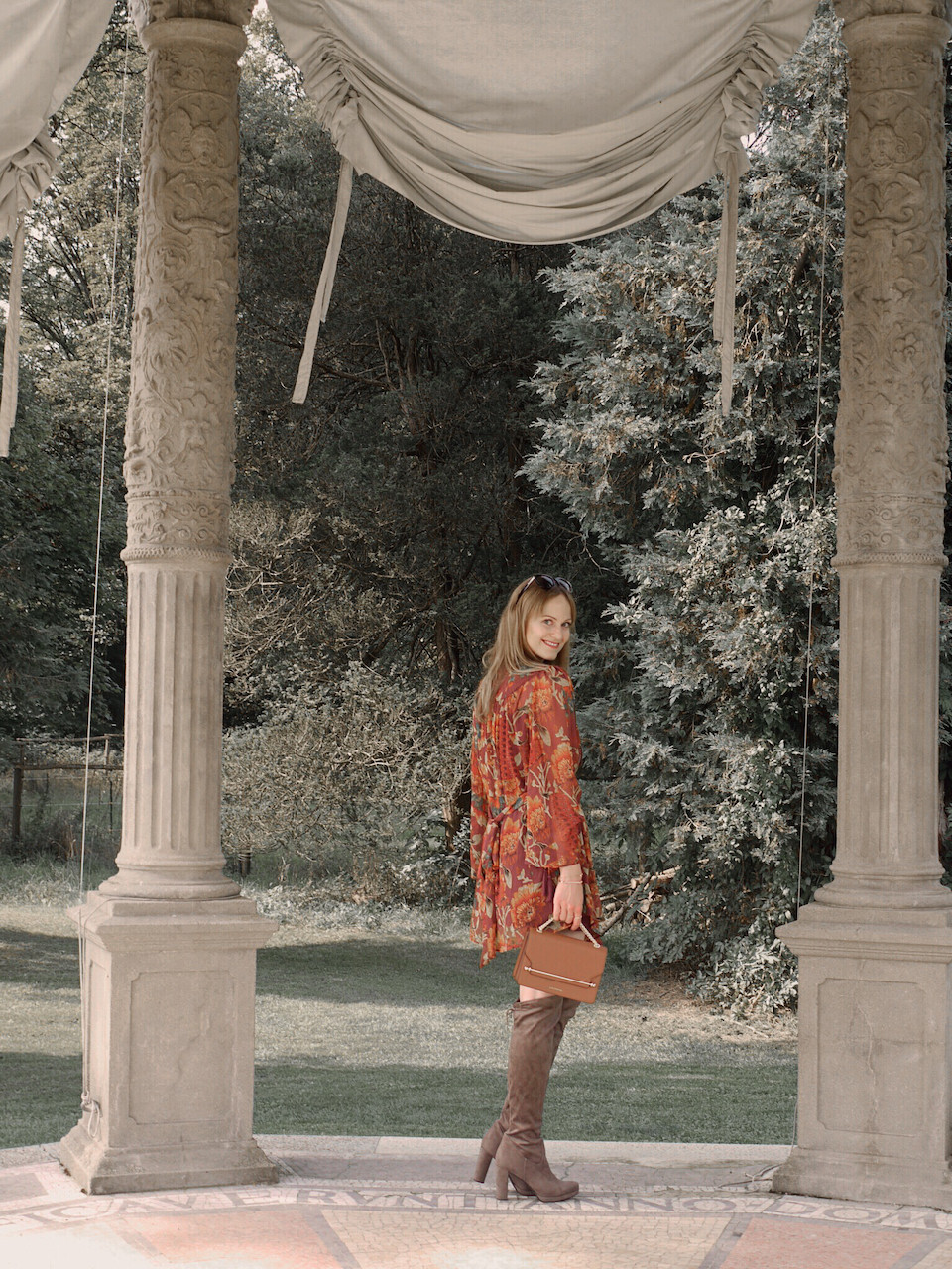 Autumn Outfit. Girl dressed in dark floral dress, over the knee boots carrying a tan bag