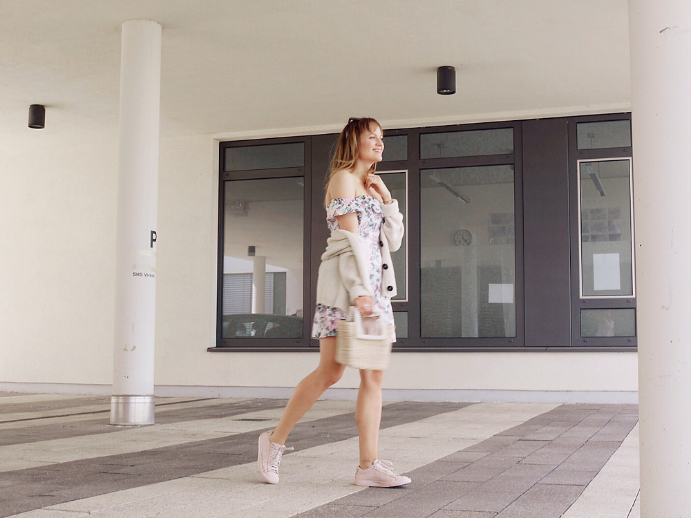 Girl dressed in floral summer dress, cardigan, pink sneakers' and basket bag