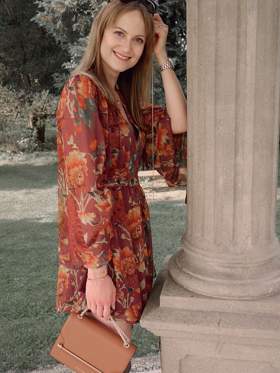 Autumn Outfit. Girl dressed in dark floral dress, over the knee boots carrying a tan bag