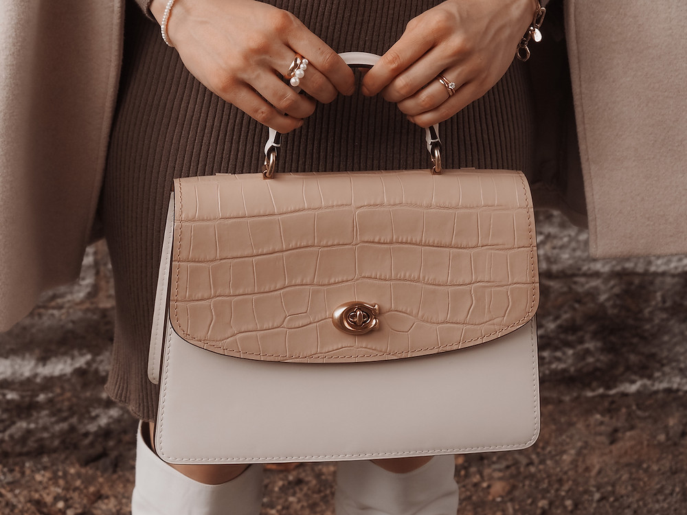 Detail shot of a Coach Parker bag in beige and white held with two hands