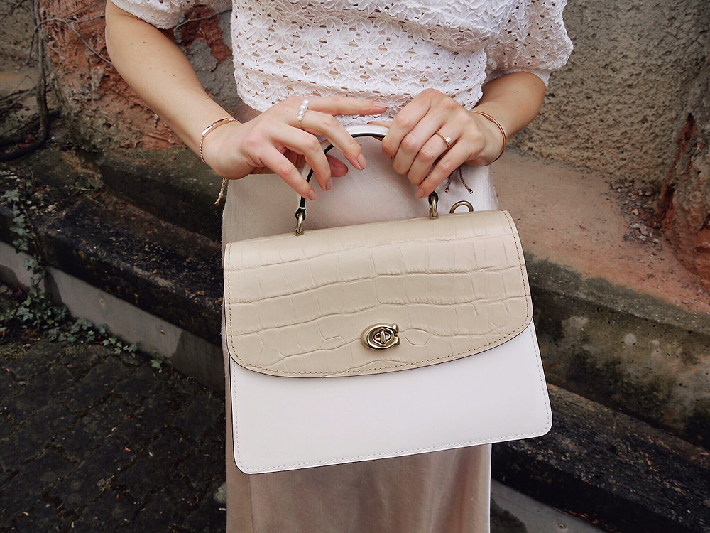 Closeup of a white and nude Coach Parker bag with croc effect leather
