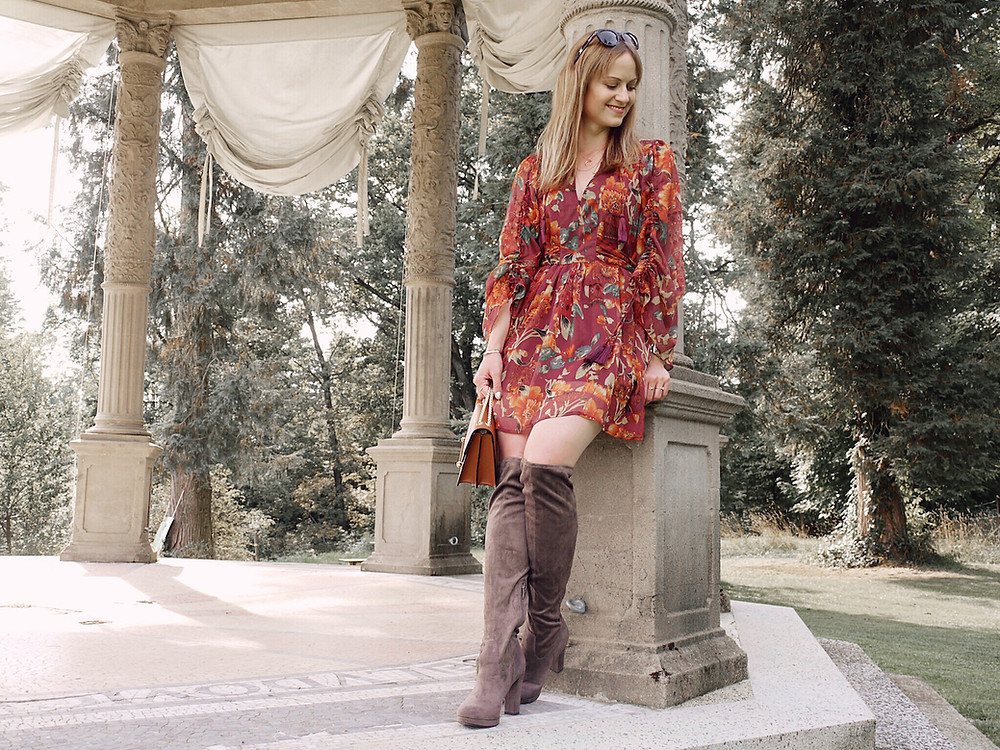Autumn Outfit. Girl dressed in dark floral dress, over the knee boots carrying a tan bag
