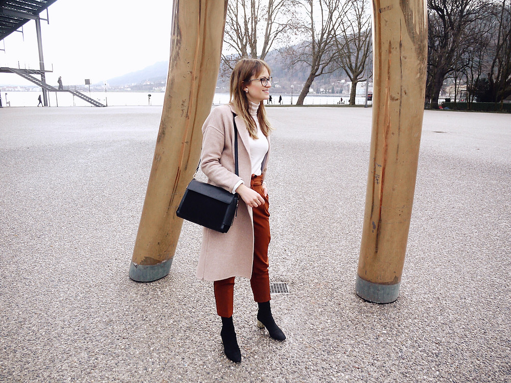 Junge Frau in einem Büro-Outfit aus Paperbag-Hose, Rollkragenpullover und weißem Blazer