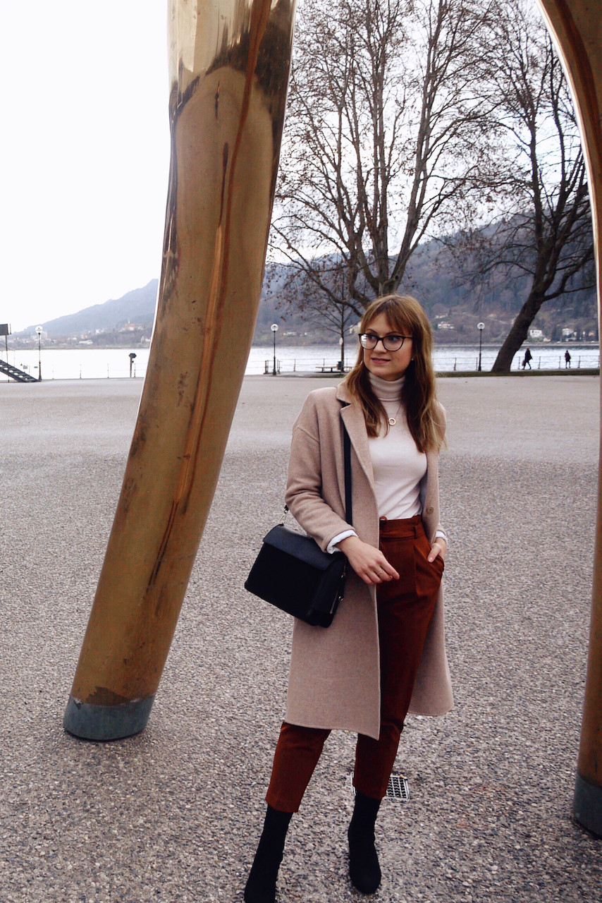 Junge Frau in einem Büro-Outfit aus Paperbag-Hose, Rollkragenpullover und weißem Blazer