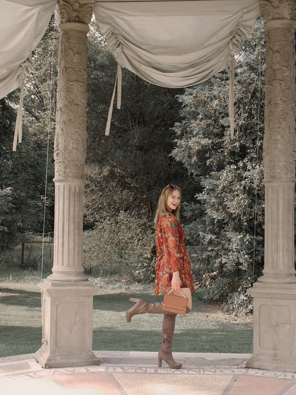 Autumn Outfit. Girl dressed in dark floral dress, over the knee boots carrying a tan bag