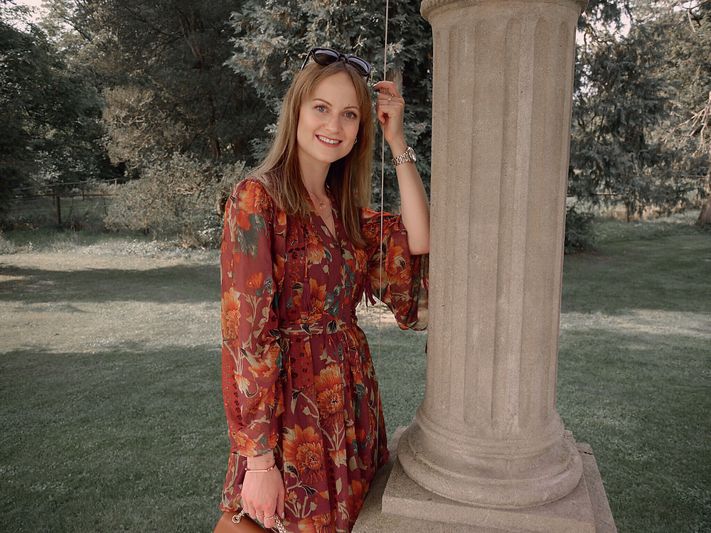 Autumn Outfit. Girl dressed in dark floral dress, over the knee boots carrying a tan bag