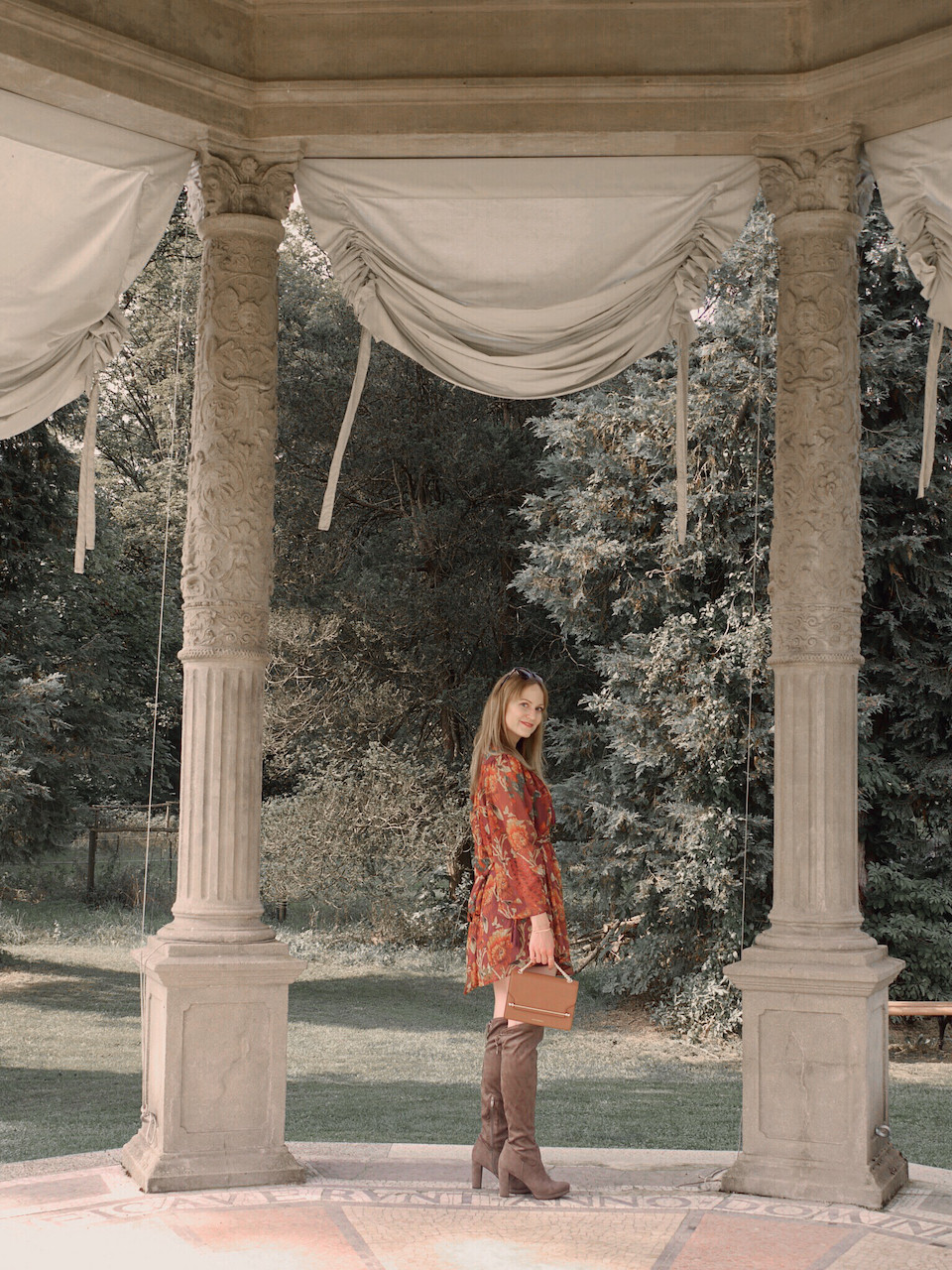 Autumn Outfit. Girl dressed in dark floral dress, over the knee boots carrying a tan bag