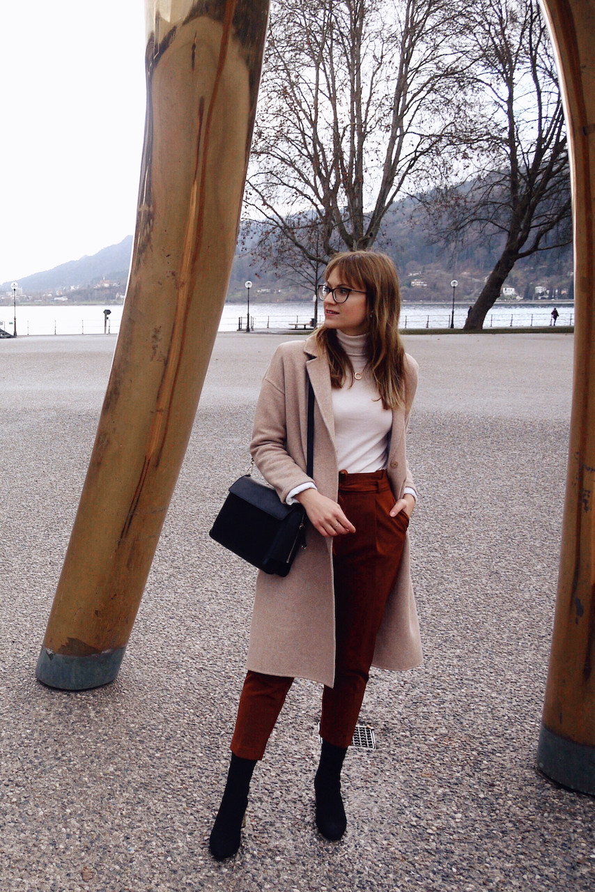 Junge Frau in einem Büro-Outfit aus Paperbag-Hose, Rollkragenpullover und weißem Blazer