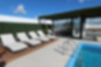 Rooftop pool area at Menesse 32 in Playa del Carmen featuring cushioned loungers, shaded pergola with outdoor seating, tropic