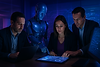 Ejecutivos colaboran con un robot humanoide frente a una pantalla táctil que despliega gráficas y visualizaciones avanzadas, representando la co-creación estratégica entre inteligencia artificial y humanos. La escena ilustra un diagnóstico IA aplicado con flujos automatizados, fragmentos de prompts personalizados y capturas de dashboards, en un entorno corporativo tecnológico, con enfoque en soluciones reales para negocios.