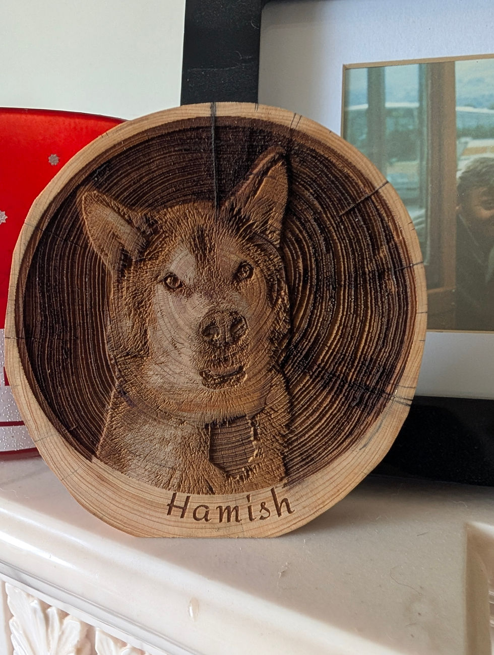 Deep carved image of Hamish on a log slice, freestanding.