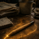 Lápiz sobre una mesa de madera, junto a una taza y papeles manuscritos, rodeado por un resplandor dorado que evoca la magia.