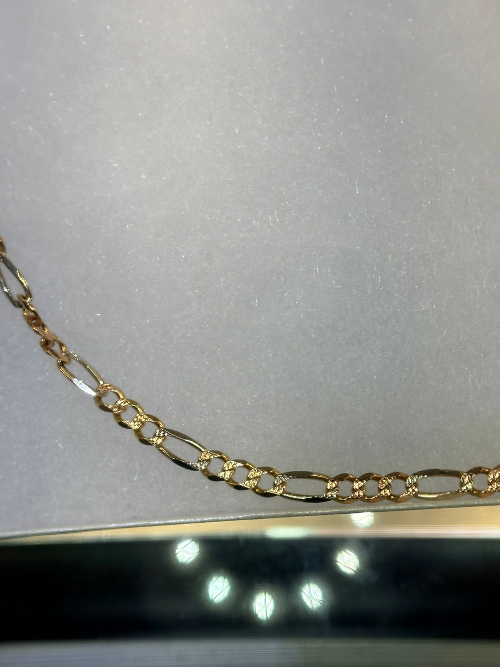 Thumbnail: Gold figaro chain necklace on a gray background