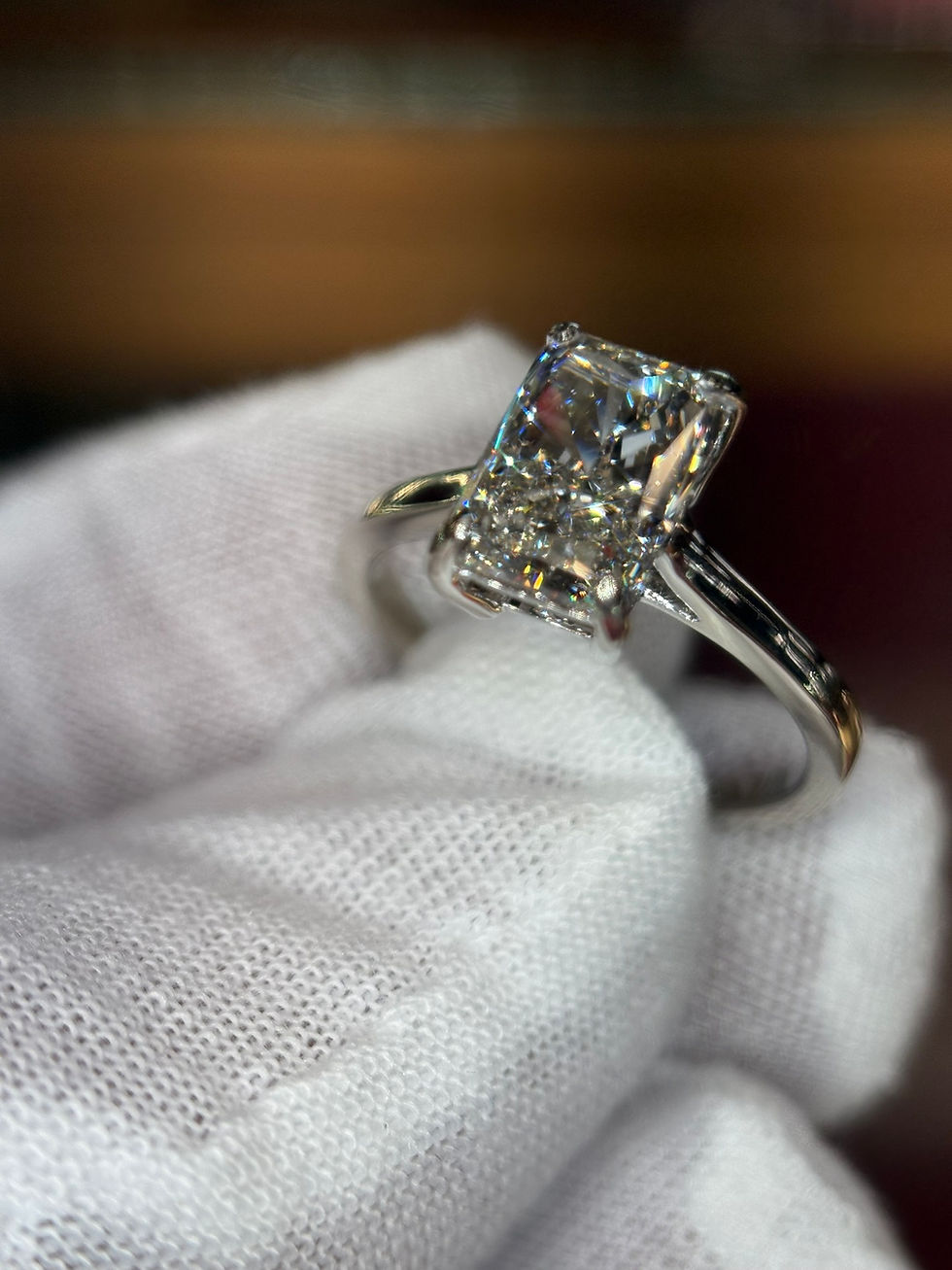 Thumbnail: Radiant cut diamond engagement ring held in a gloved hand