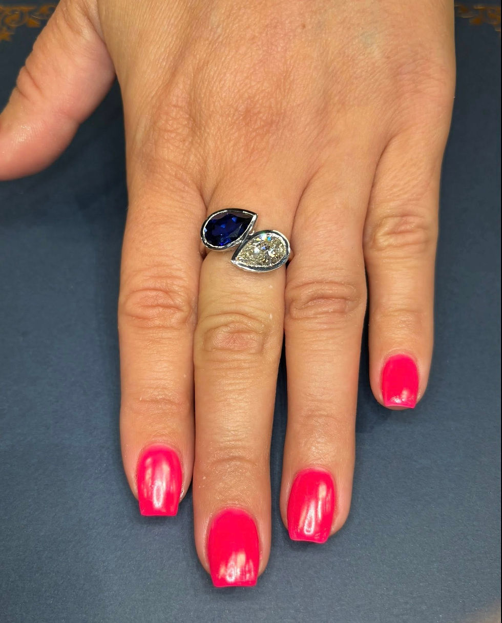 Thumbnail: Two-stone pear-cut ring worn on a hand with pink nails