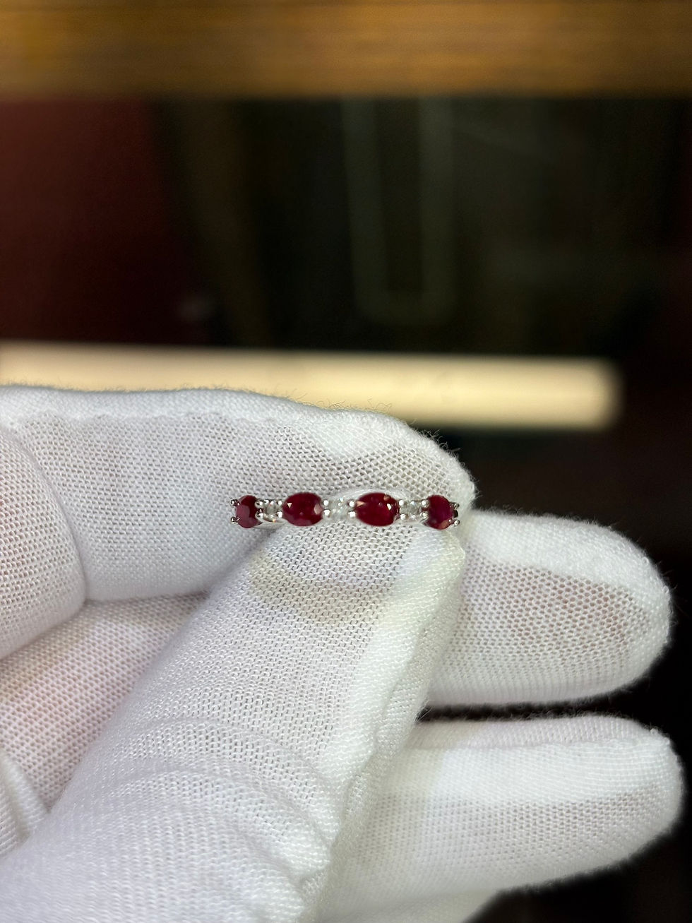 Thumbnail: Silver band with four oval rubies held by gloved hand