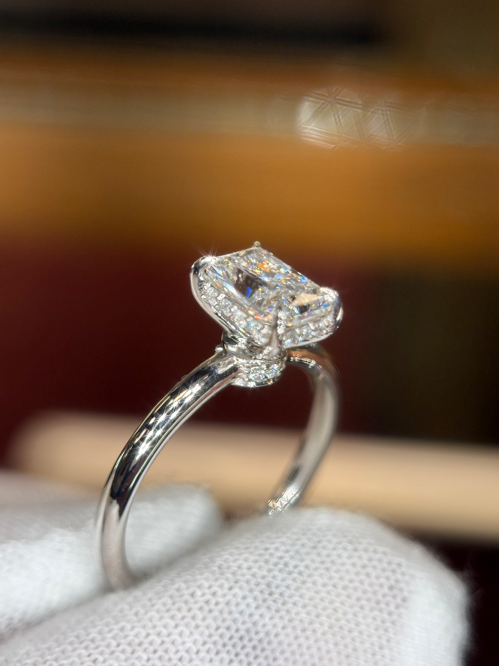 Thumbnail: Emerald cut diamond ring with a halo setting on a silver band