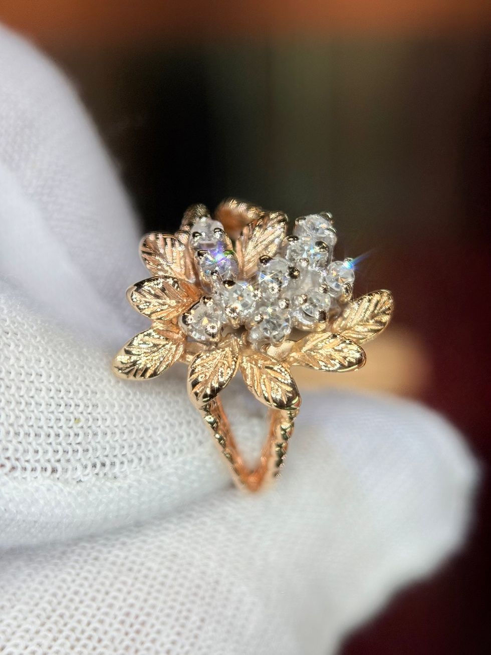 Thumbnail: Gold floral diamond ring with leaf details being held.