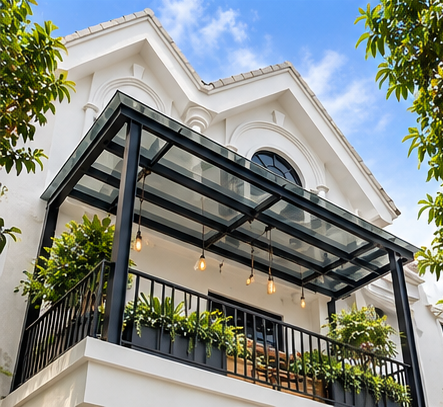 Two-story landed house with a black-framed glass balcony canopy, arched windows, pendant lights, and potted plants.
