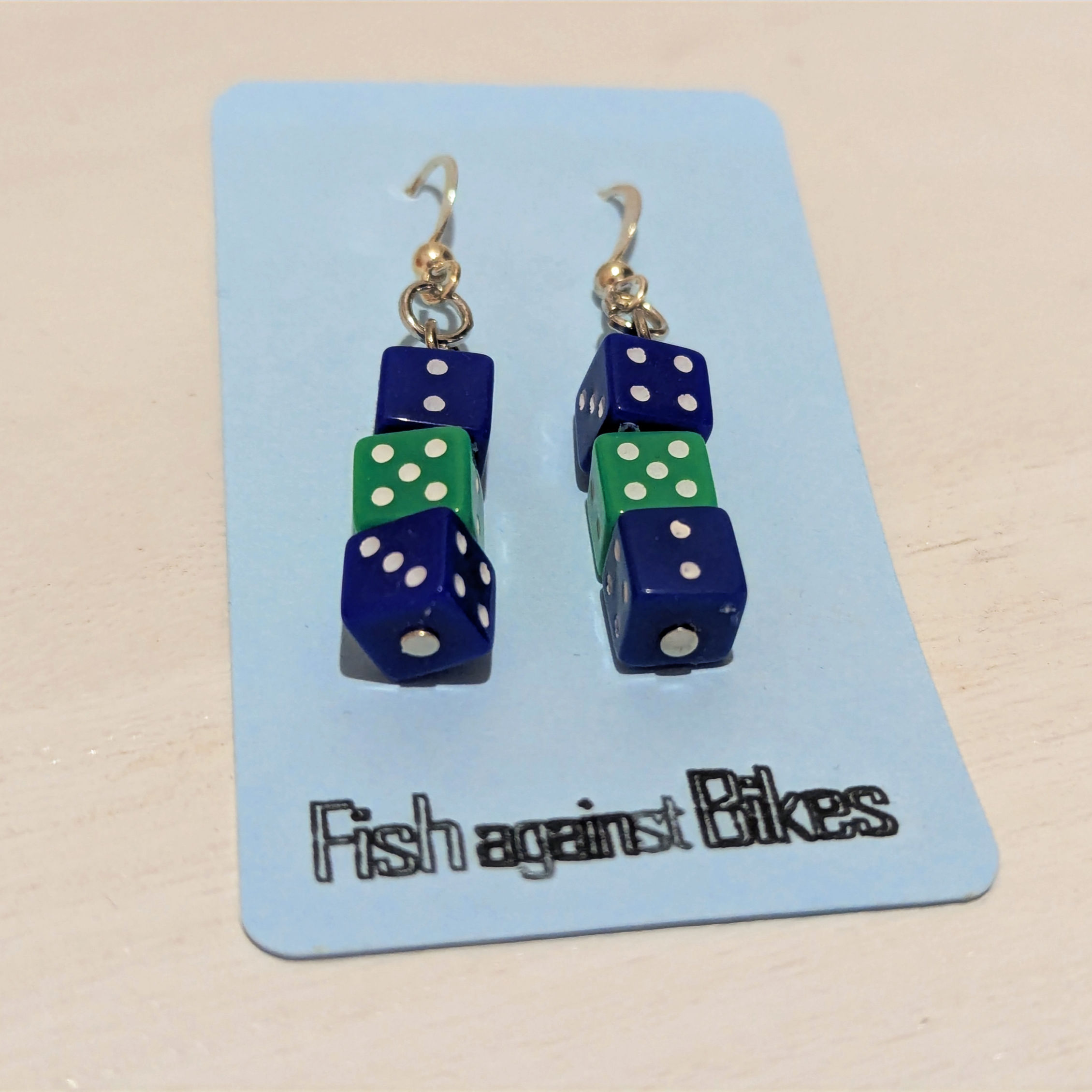 Two mini blue and one mini green dice on each earring, on blue backing card.