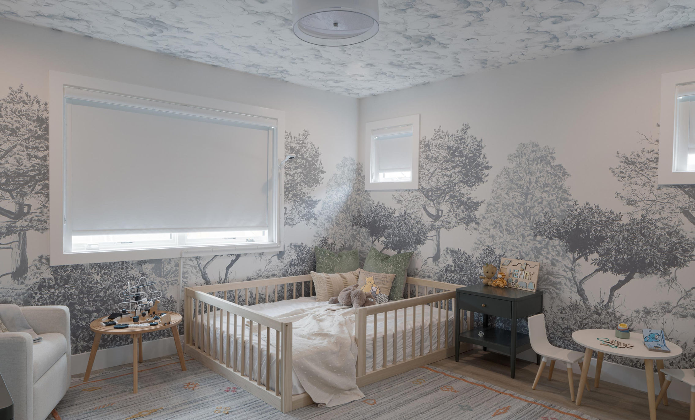 Nursery with forest mural and low wooden floor bed.