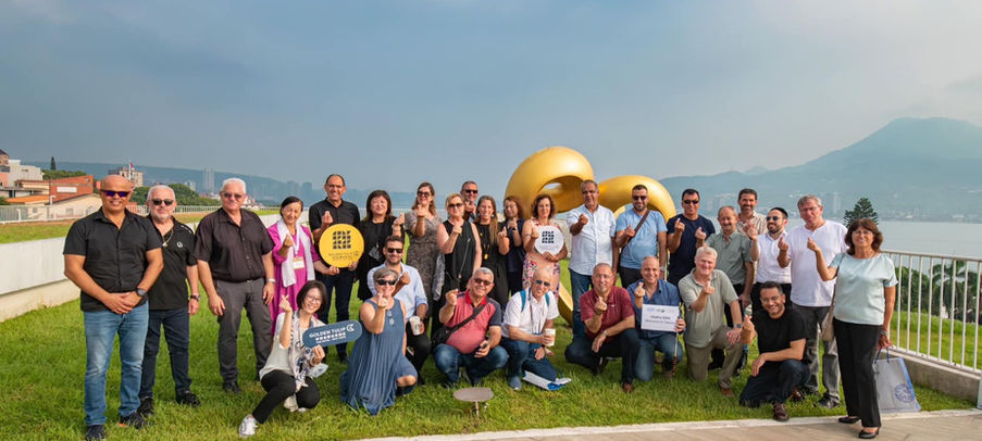 קבוצת אנשים מצטלמת על דשא עם בלונים זהובים, יום שמח באוויר הפתוח