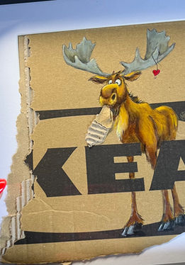Handbemalter Elch auf zerrissenem IKEA-Karton, illustriert mit rotem Herz auf recyceltem Hintergrund