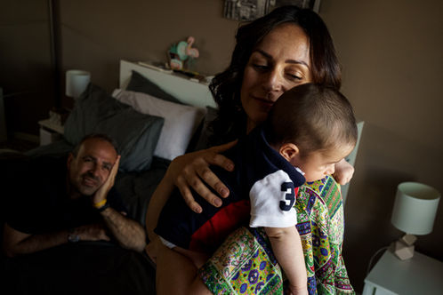 mom holds baby while dad looks at them lovingly