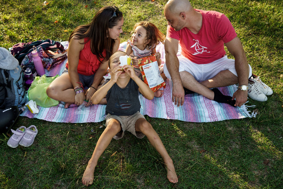boy eats crumbs from a cracker wrapper while girl looks at her parents