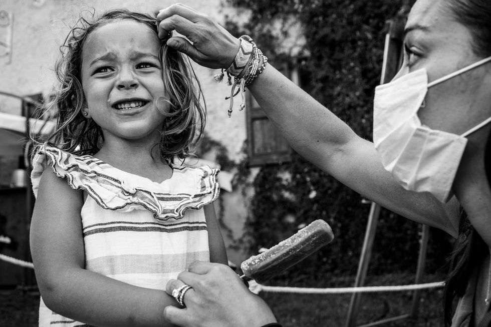 girl cries while holding a lollipop and mom comforts her