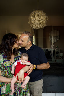 mom and dad kiss while holding their baby