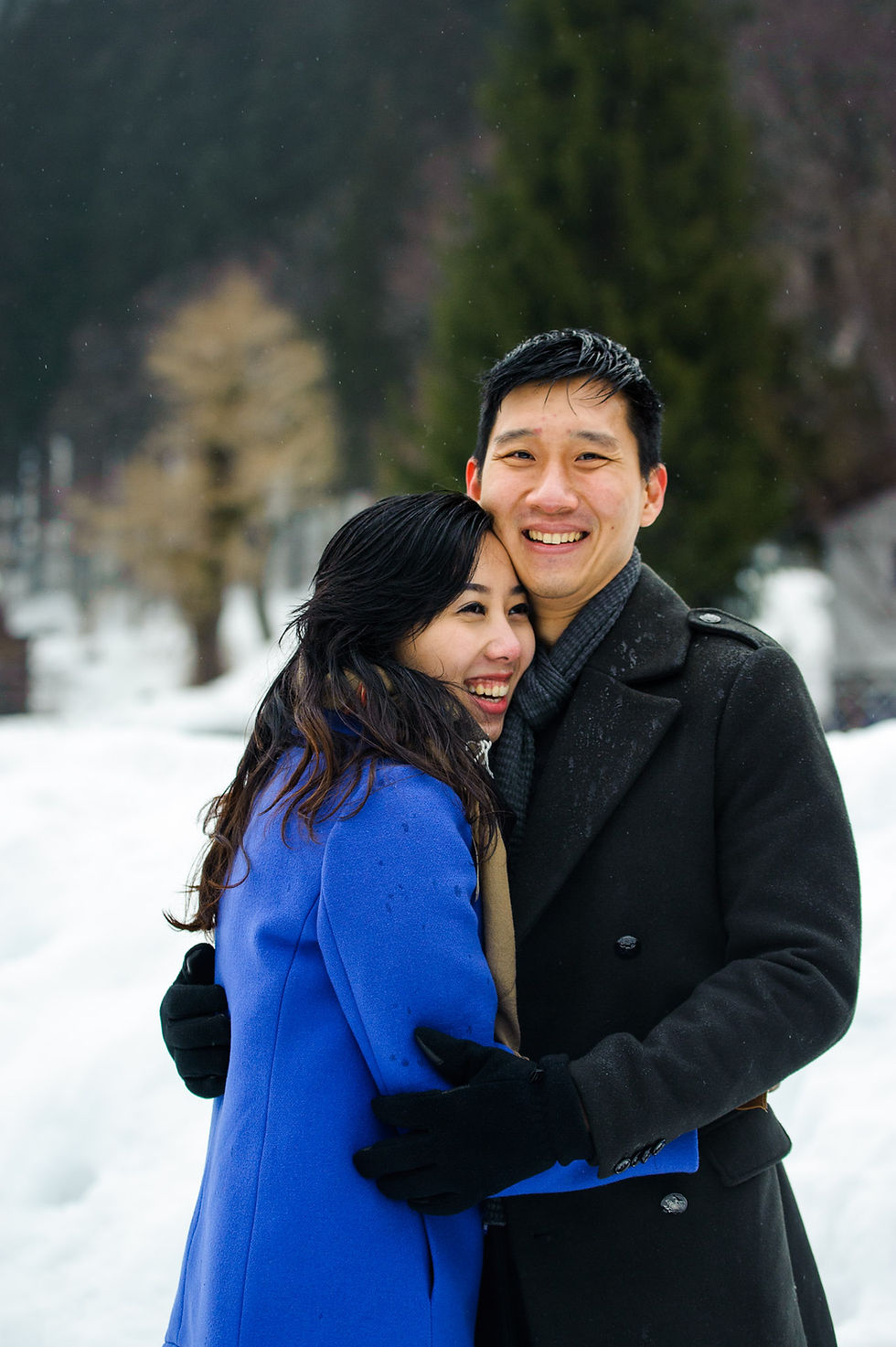Sin puts his arms around Mira as they laugh together in Shirakawago