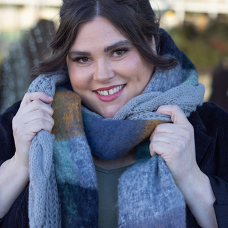 a woman smiling holding a scarf that is wrapped on her neck