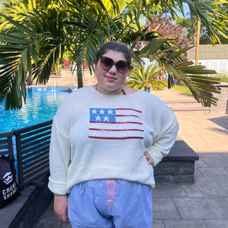 a plus size woman wearing a white sweater with an American flag on it and blue shorts