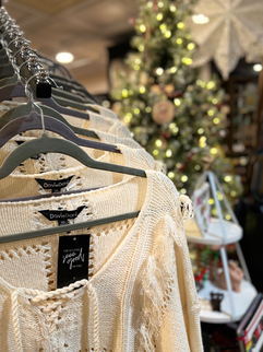 a close up of sweaters hanging on. arack in the curvy corner boutique