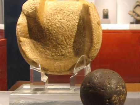 A solid rubber ball used (or similar to those used) in the Mesoamerican ballgame, 300 BCE to 250 CE, Kaminaljuyu. The ball is 3 inches (almost 8 cm) in diameter, a size that suggests it was used to play a handball game. Behind the ball is a manopla, or handstone, which was used to strike the ball, 900 BCE to 250 CE, also from Kaminaljuyu. Photo Credit: Wikipedia