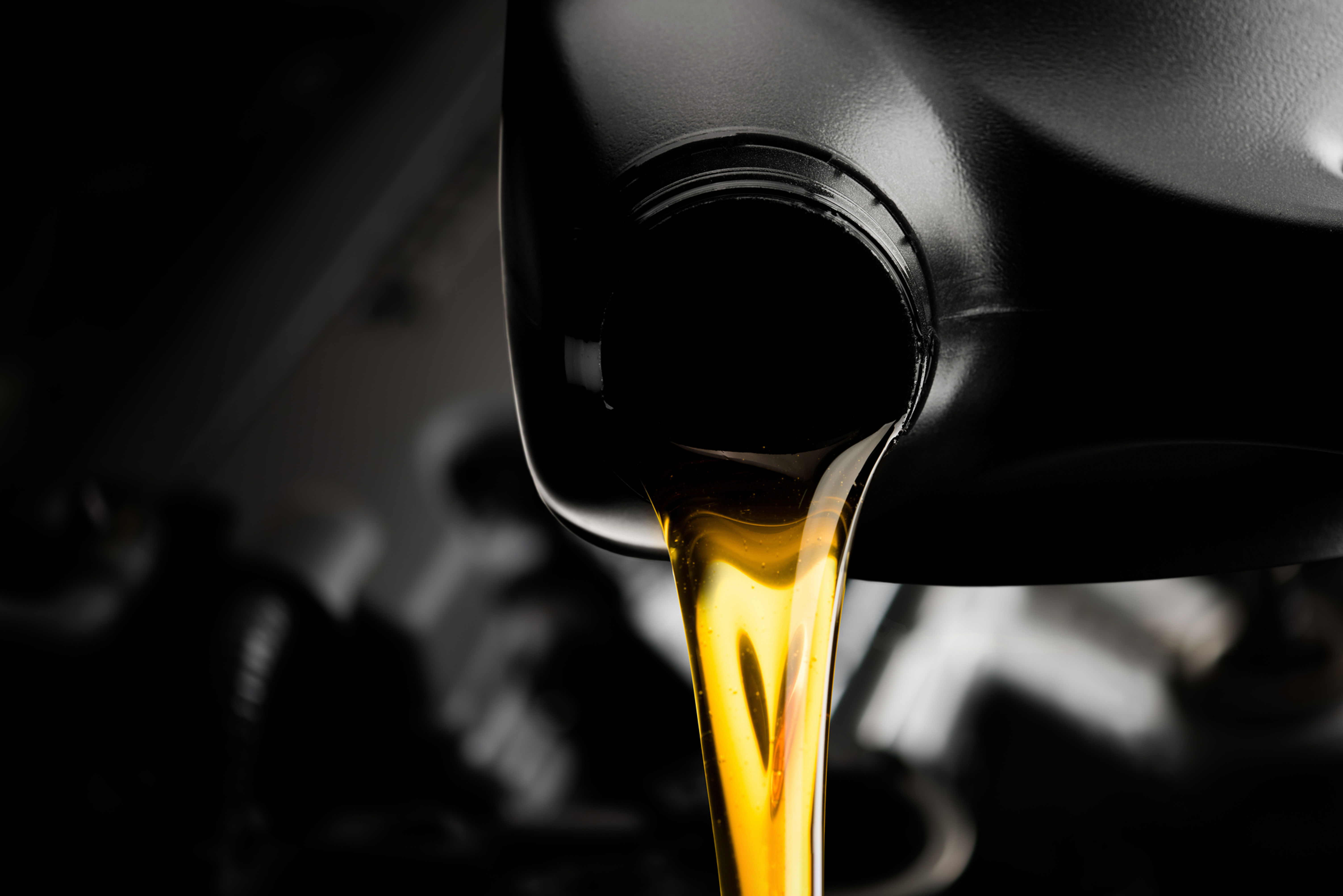 Mechanic performing oil change on a Honda sedan.