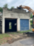 An excavator breaking a warehouse