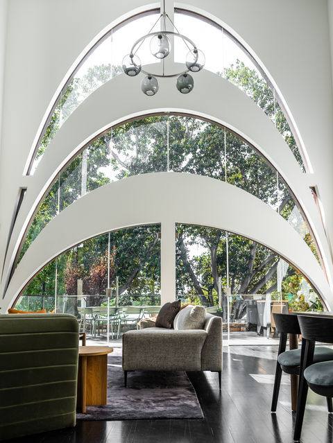A interior design photograph of an open dining and living room with furniture and natural light streaming in large windows in the background