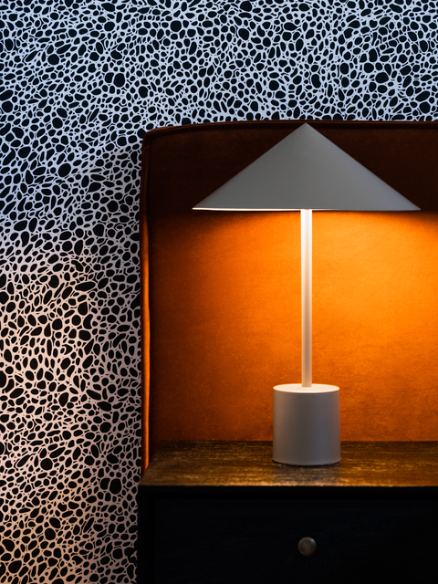 An interior design photograph featuring a bedside table with a lamp