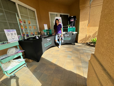 A photo of a women in Front of her tables with her merchandise for Mermaid Kove LLC