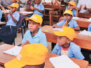 Primary school students sit at desks in a school in Mozambique.