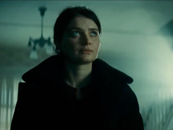 A woman looks slightly upward with a solemn look on her face.