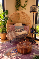 a rattan egg chair layered with cushions in a garden space