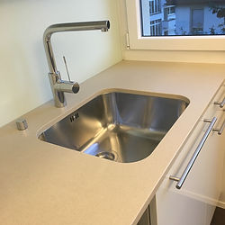 Moderne Küchenspüle mit Fenster und heller Arbeitsfläche, vollständig gereinigt