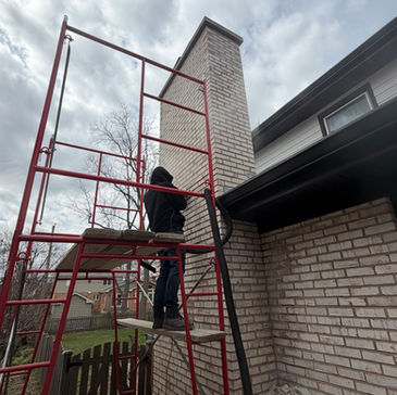 Worker on scaffolding next to a brick chimney.
